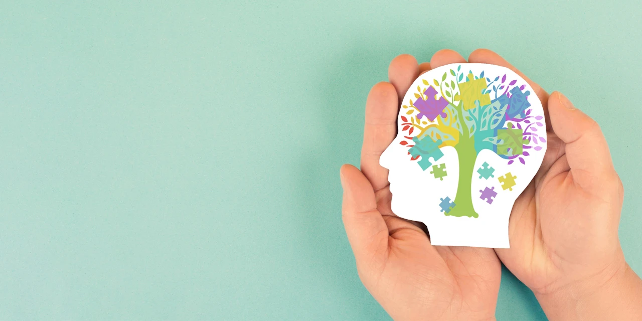 adhd illustratie van hoofd met kleurrijk brein en puzzelstukken in hand.