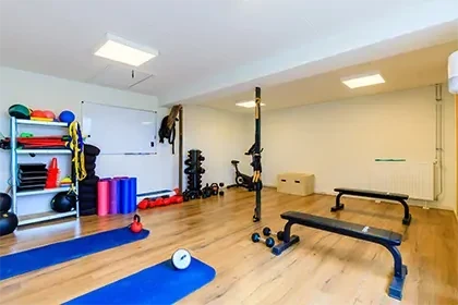 meerlo-sportruimte Sportruimte met houten vloer, sportbankjes, yogamatten en gewichten tegen de muur.