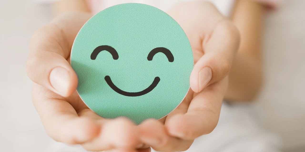 Een blije smiley van papier in de hand van een vrouw. 