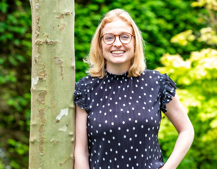 Tessa, lid van het team van Connection SGGZ, staat vriendelijk lachend in een groene omgeving.