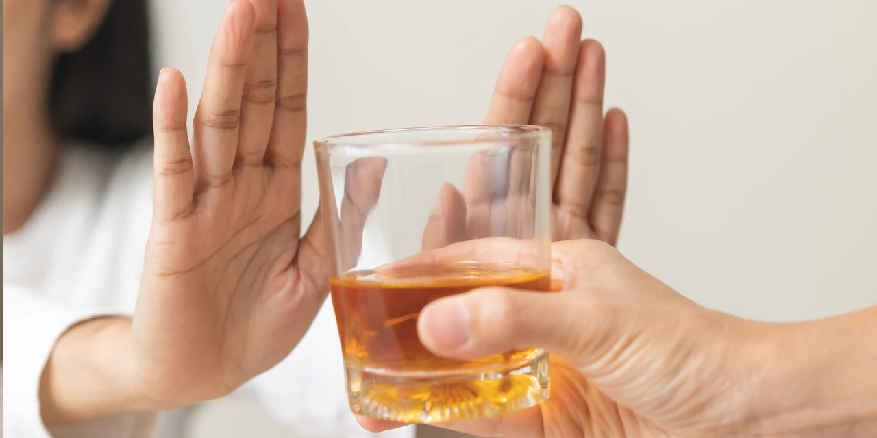 Persoon houdt hand op voor glas alcohol en weigert een drankje.