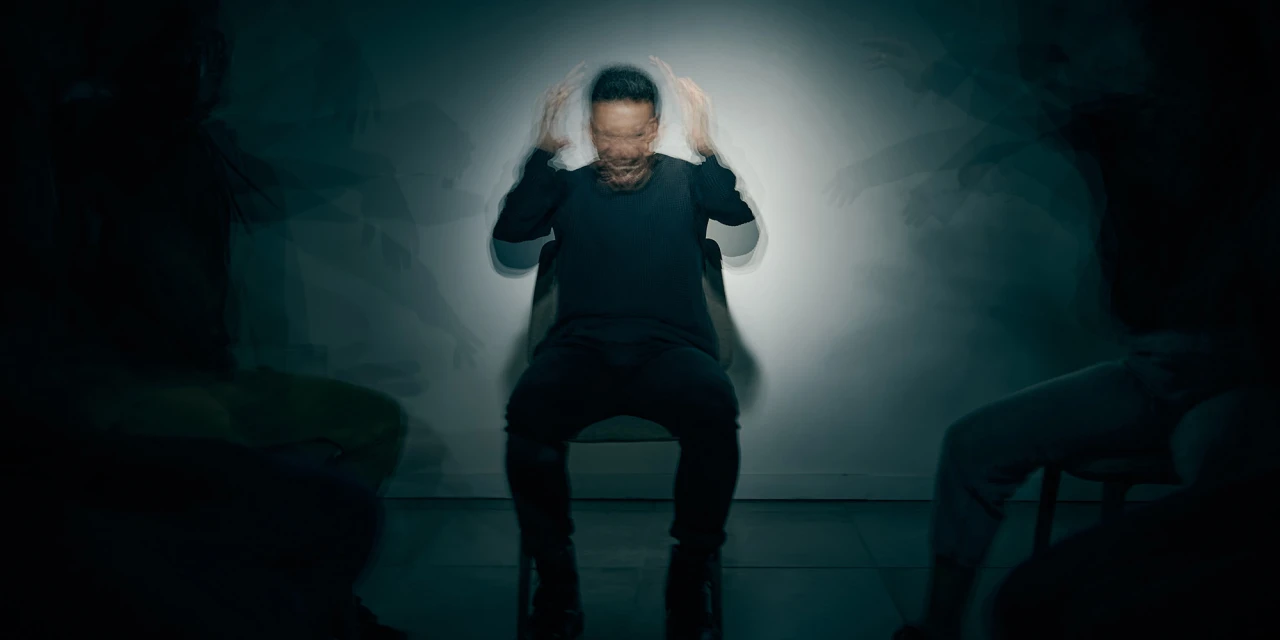 Man met angstige expressie en schaduwen die hem omringen, symbool voor bipolair.