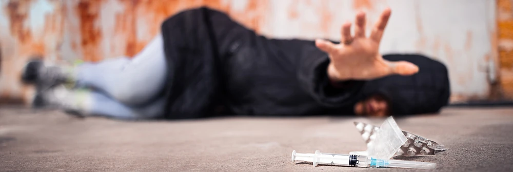 Wat is craving? Persoon met sterk verlangen naar drugs en een spuit.