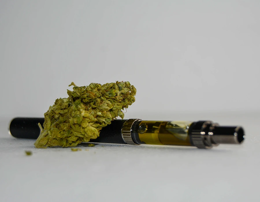 THC-vape met cannabisbloem op een witte ondergrond.