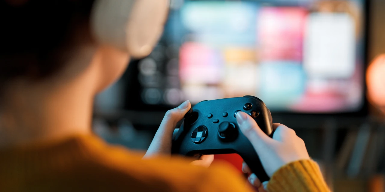 Persoon speelt videogame met controller en koptelefoon mogelijk last van gameverslaving.