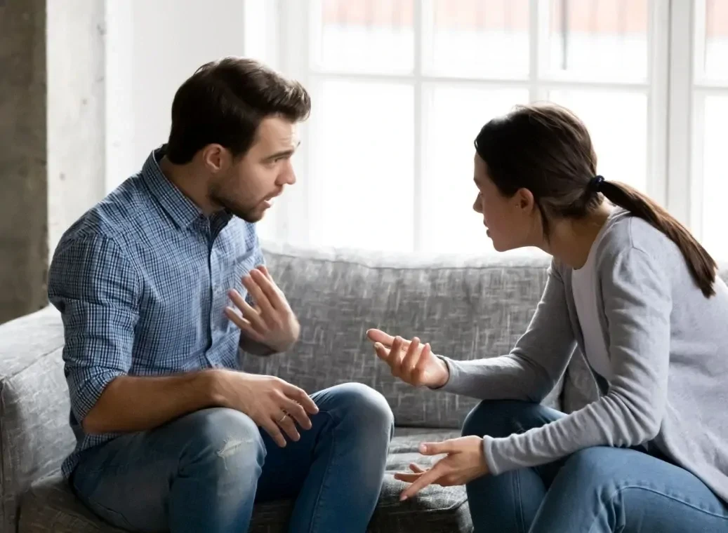 man-en-vrouw-relatieproblemen-door-alcohol Man en vrouw zittend tegenover elkaar op bank, maken ruzie vanwege relatieproblemen door alcohol.