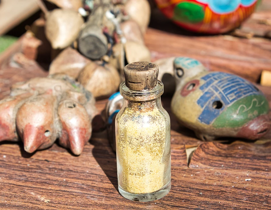 Flesje met poeder en rituele objecten op tafel, verwijzend naar gebruik van DMT.