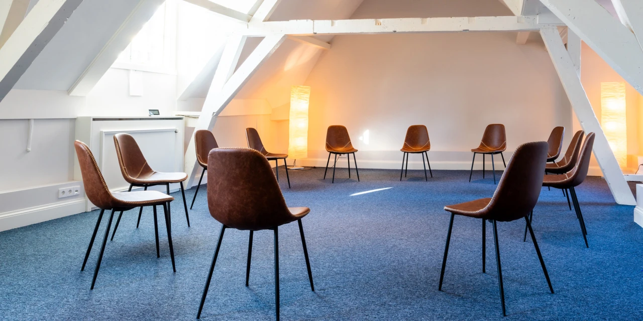 Groepsruimte met stoelen in cirkel voor therapie.