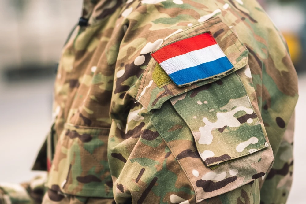 Soldaat in camouflage uniform met het Nederlandse vlaggenembleem, SZVK.