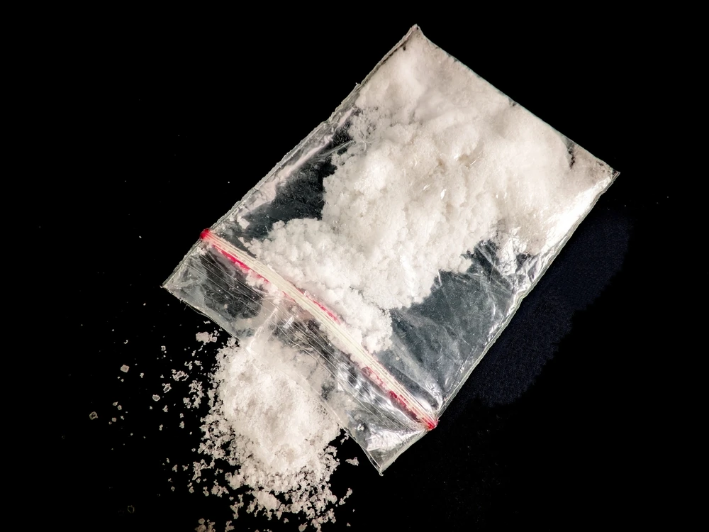 Doorzichtig zakje met wit poeder van de drug miauw miauw op zwarte achtergrond.