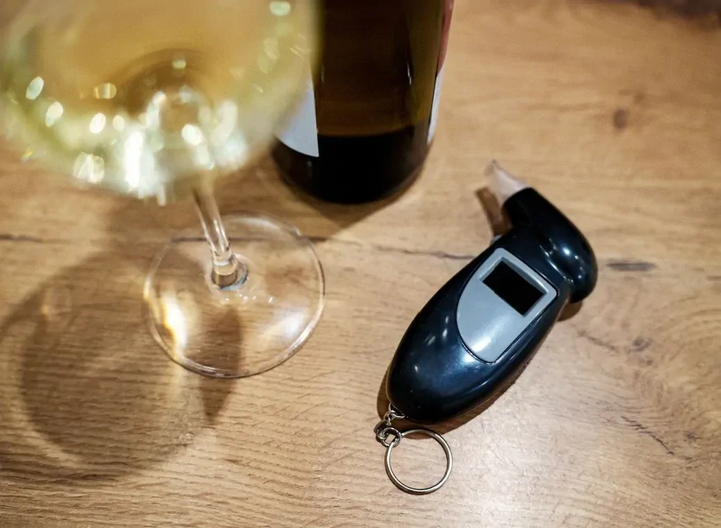 Test voor alcoholpromillage, wijnglas en wijnfles op houten ondergrond.