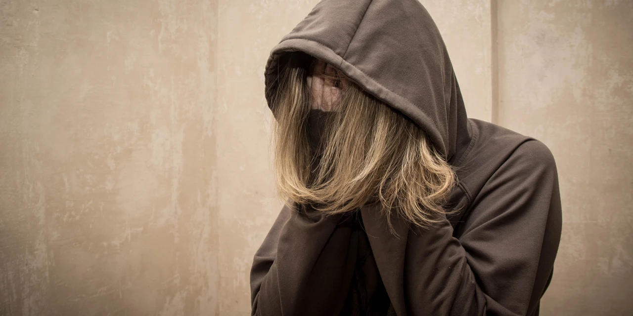 Persoon met hoodie en hoofd in handen worstelt met pornoverslaving.