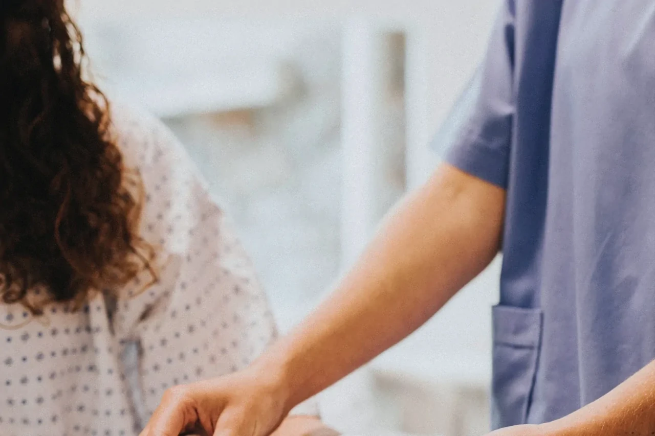 Close-up van medisch beeld waarbij je de schouder van de patient ziet en de armen van een dokter.