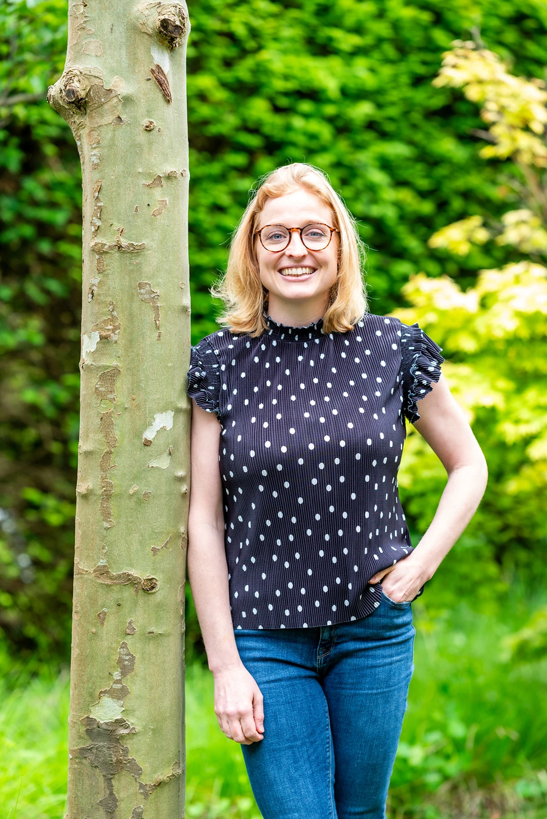 Tessa, lid van het team van Connection SGGZ, staat vriendelijk lachend in een groene omgeving.