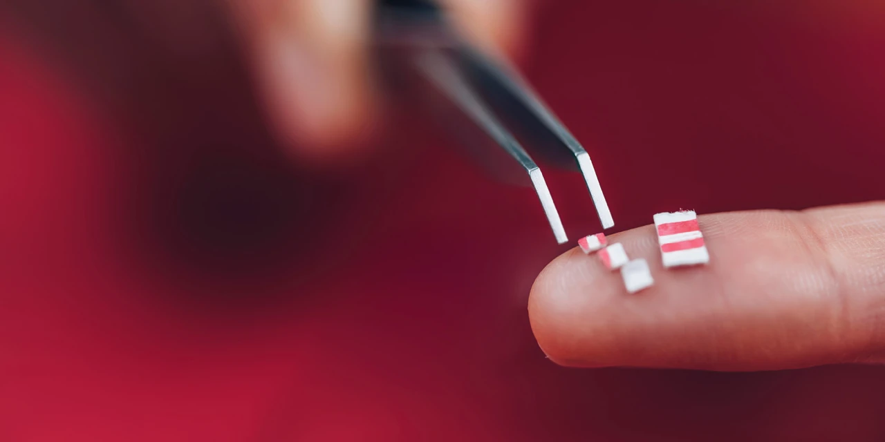 Kleine stukjes blotter met LSD op vinger vastgehouden met pincet.