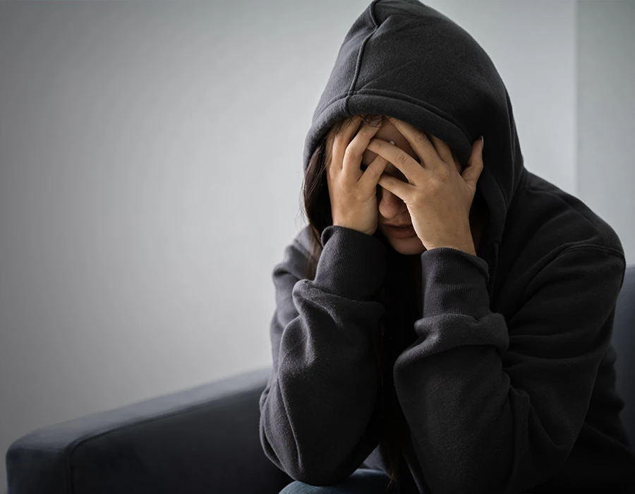 Persoon zit met hoofd in handen en oogt somber door verslaving.
