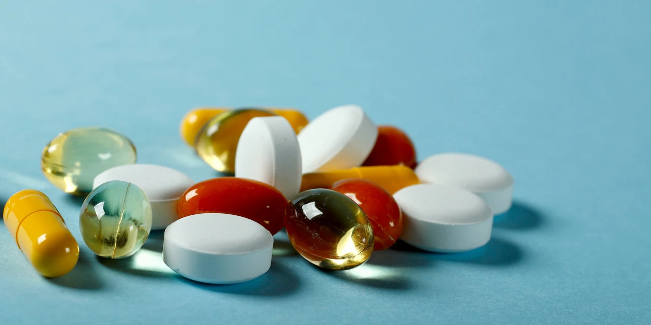 Verschillende pillen en capsules op blauwe achtergrond, beeld van medicatiegebruik.