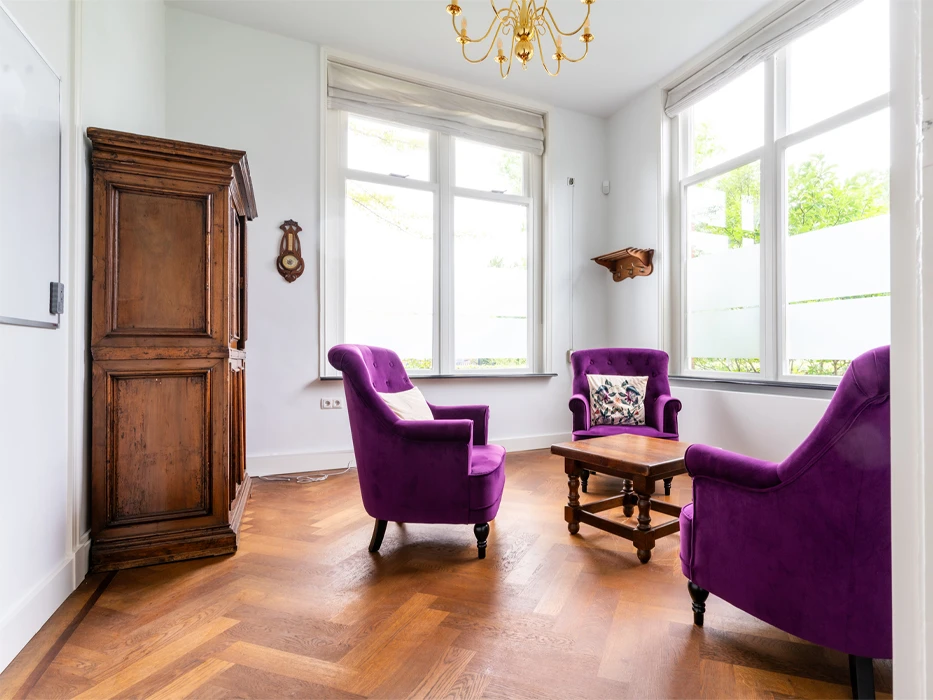afkickkliniek-fazantlaan-behandelruimte Therapieruimte poliklinische verslavingszorg Eindhoven, met 3 paarse fauteuils, salontafel en kast.