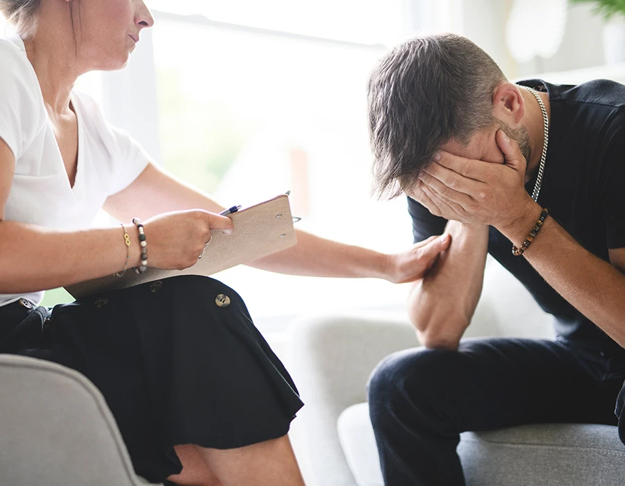 Zorgprofessional praat met een verdrietige man tijdens een gesprek over drugsgebruik.