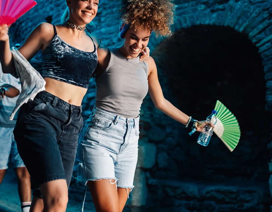 Twee vrouwen wandelen met waterflessen tijdens een warme dag.
