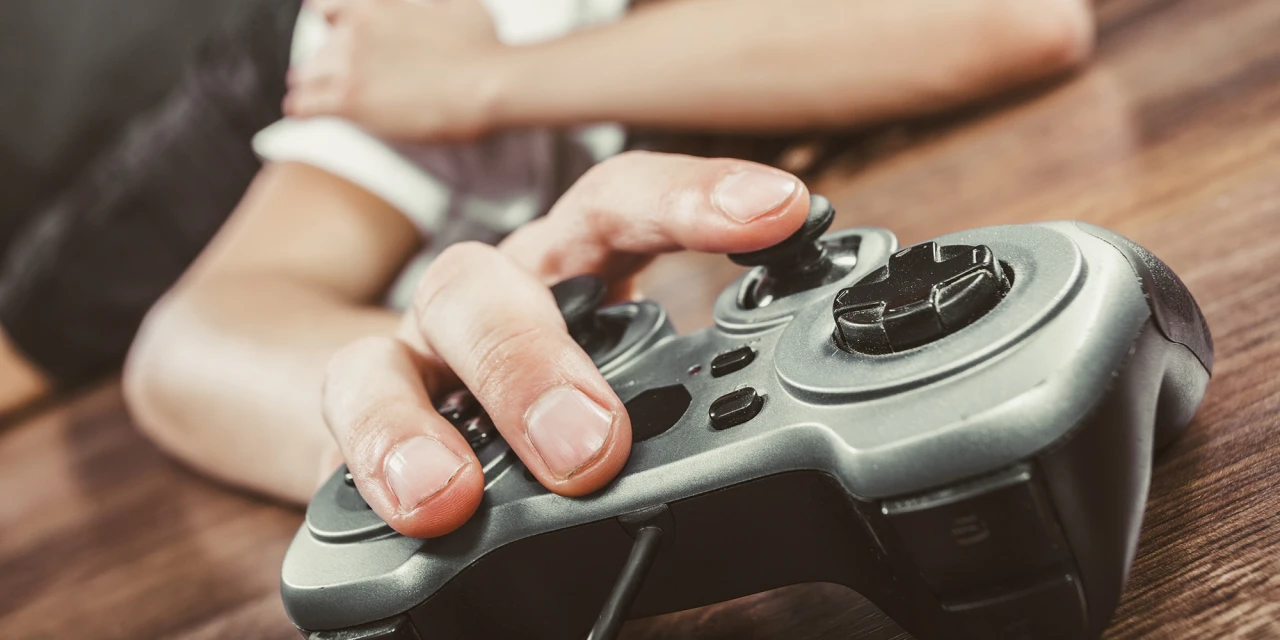 Persoon ligt uitgeput naast controller door gedragsverslaving aan gamen.