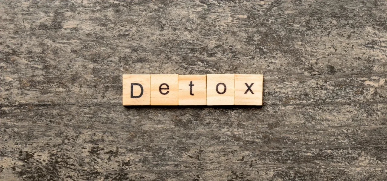 houten-blokjes-spellen-detox Houten scrabble blokjes spellen het woord detox op een grove ondergrond.