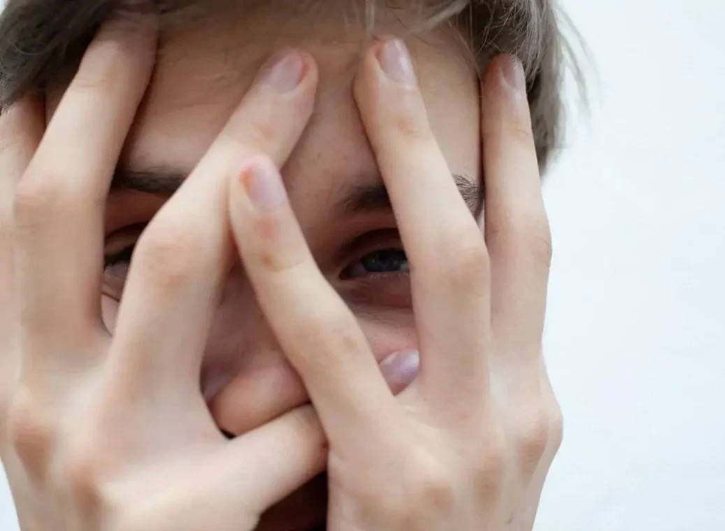 handen-voor-gezicht Close-up van het gezicht van een man met handen voor het gezicht.