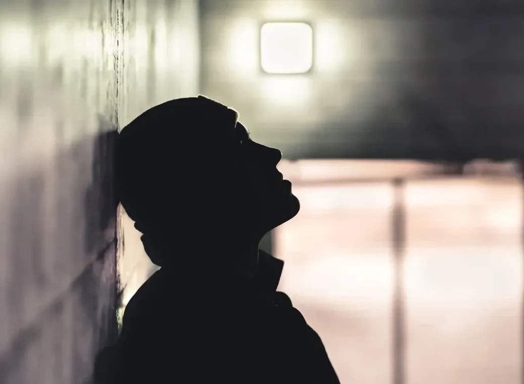 silhouette-man-tegen-muur Silhouette van een man die tegen een muur aan leunt.