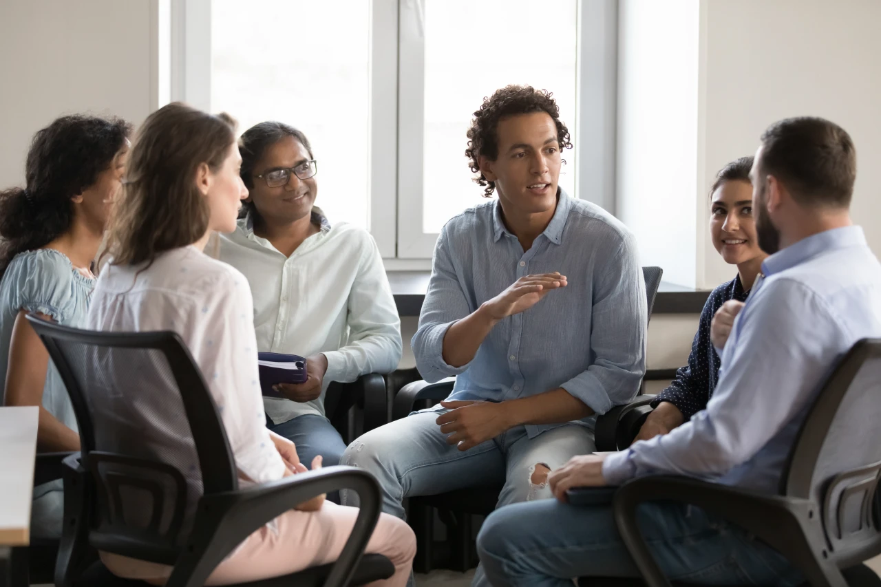 Groep-mensen-bij-erkend-leerbedrijf Erkend leerbedrijf waar een groep jonge mensen aan een kringgesprek deelnemen.