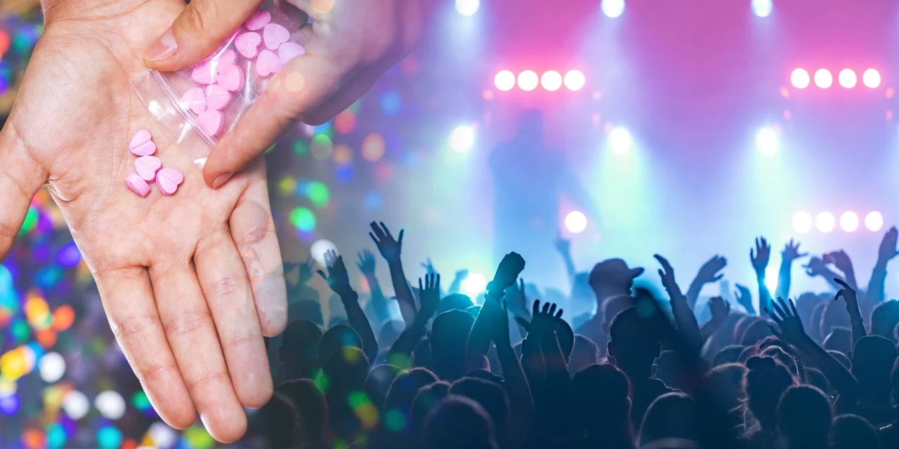Hand met roze drugs tijdens een festival met dansende menigte.