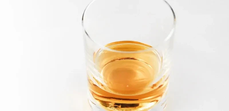 glas alcohol Een glas sterke alcoholische drank op een witte achtergrond.