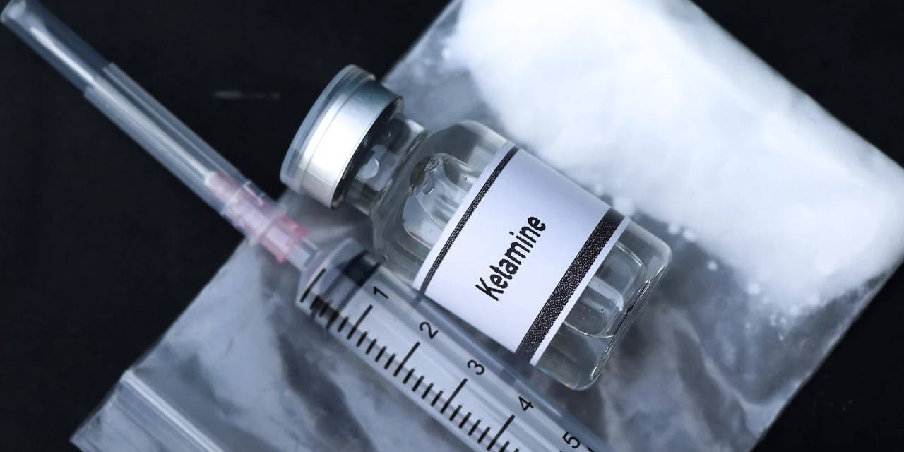 Spuit en flesje ketamine op een plastic zak gebruikt bij ketamineverslaving.