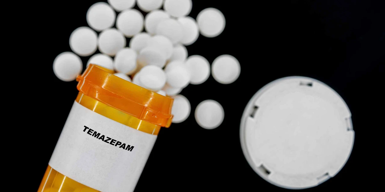 Oranje medicijnfles met het label temazepam en witte pillen verspreid eromheen.