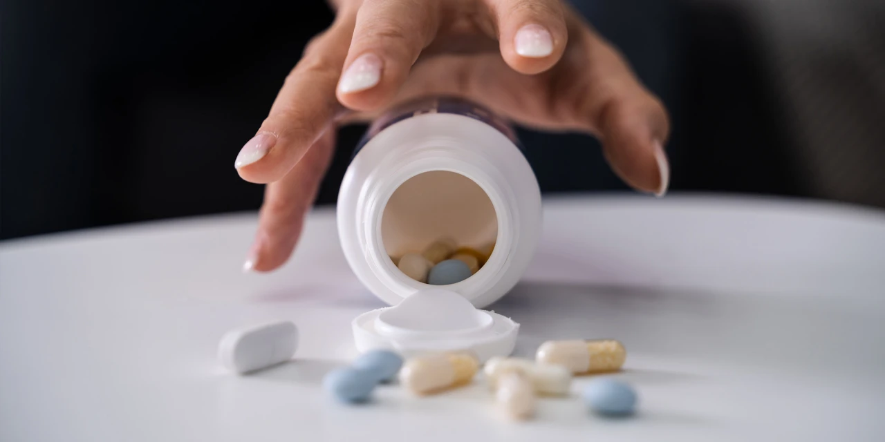 Hand kantelt pot met pillen als beeld van opioïdenverslaving en controleverlies.