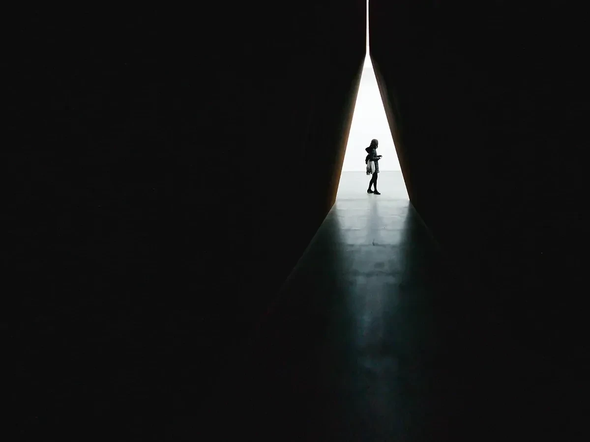 silhouette-vrouw-driehoek Donkere foto met het silhouette van een vrouw in de verte zichtbaar in een lichtgevende driehoek.