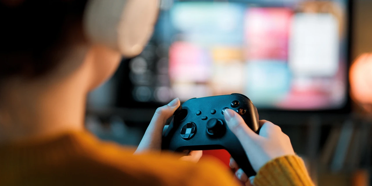 Behandeling gameverslaving bij iemand die geconcentreerd gamet op een console.