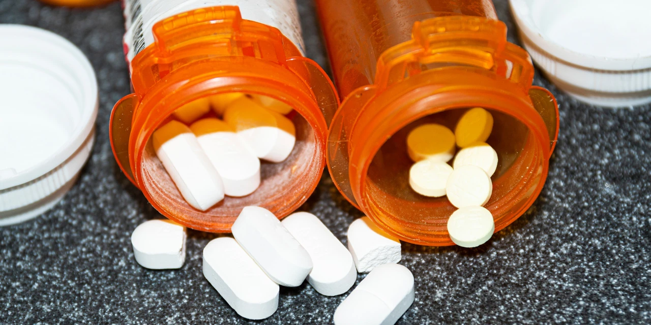 Tabletten en capsules uit pillendoosjes verspreid op tafel.
