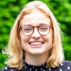 Tessa, lid van het team van Connection SGGZ, staat vriendelijk lachend in een groene omgeving.