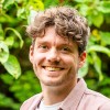 Jacob, lid van het team van Connection SGGZ, staat vriendelijk lachend in een groene omgeving.